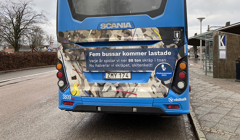 En buss med budskap. På bussen baksida står det "Fem bussar kommer lastade. Varje år spolar vi ner 88 ton skräp i toan. Nu halverar vi skräpet, skitenkelt"